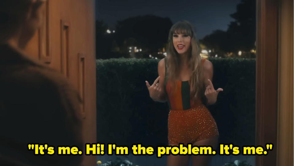 Taylor Swift stands in front of a door at night, wearing a stylish outfit, and says, "It's me. Hi! I'm the problem. It's me."