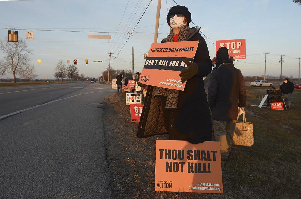 Karen Burkhart holds a sign across the road from the Federal Correctional Complex in Terre Haute, Ind., to protest the scheduled execution of Lisa Montgomery, Tuesday, Jan. 12, 2021. An appeals court granted a stay of execution Tuesday for Montgomery, convicted of killing a pregnant woman and cutting the baby from her womb in the northwest Missouri town of Skidmore in 2004. (Joseph C. Garza/The Tribune-Star via AP)