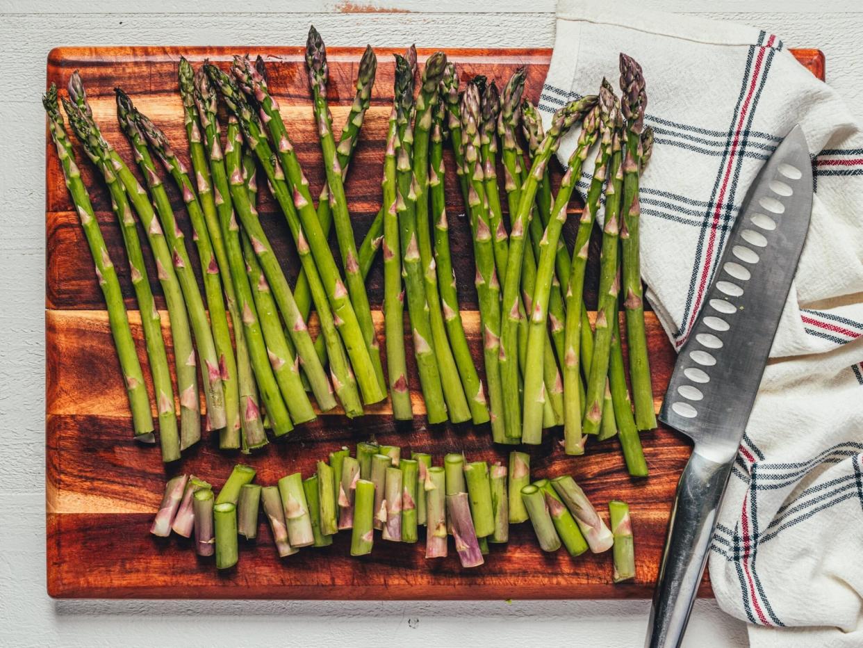 asparagus with ends trimmed on a wooden cutting board