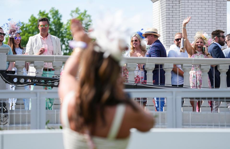 Nicole Steele, on the outside of the Paddock, waves to her friend Kim Carver, in the foreground, as the two talk while attending Thurby May 2, 2024 at Churchill Downs in Louisville, Kentucky.