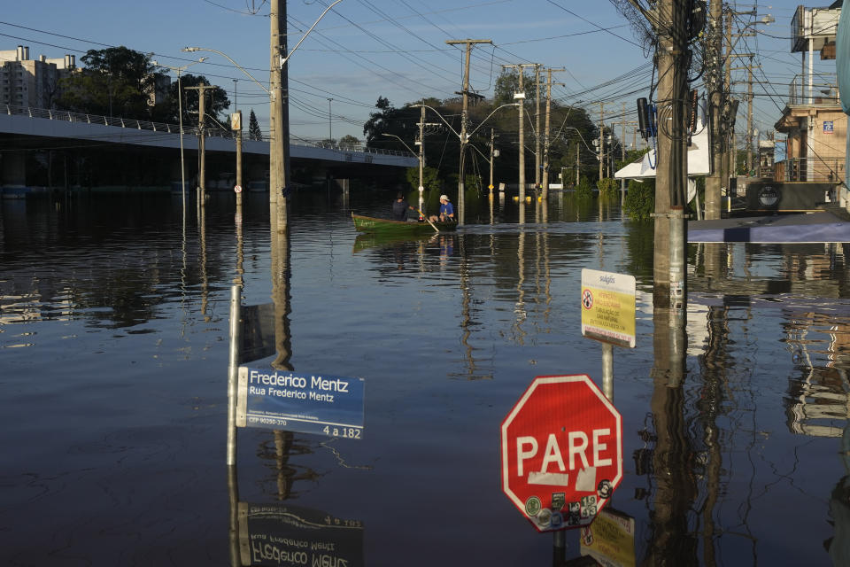 Residents navigate a boat through a street flooded by heavy rains, in Porto Alegre, Rio Grande do Sul state, Brazil, Thursday, May 9, 2024. (AP Photo/Andre Penner)
