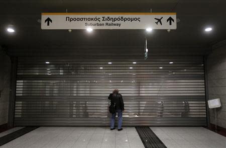 A commuter stands in front of the closed entrance of a suburban railway station during a general 24 hour labour strike in Athens November 6, 2013. REUTERS/John Kolesidis