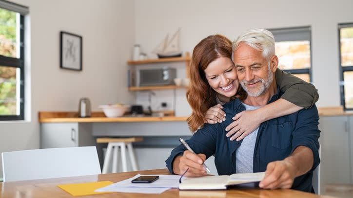 A couple does some rough math at the kitchen table to determine whether they can afford to retire at 60.