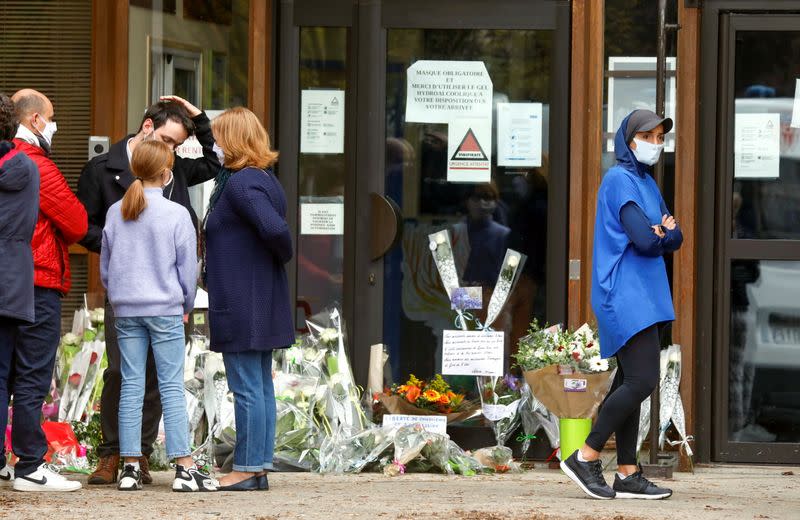 People bring flowers to the Bois d'Aulne college after the attack in the Paris suburb of Conflans St Honorine