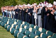 Bosnian Muslims pray in front of coffins during a mass funeral in the village of Hambarine