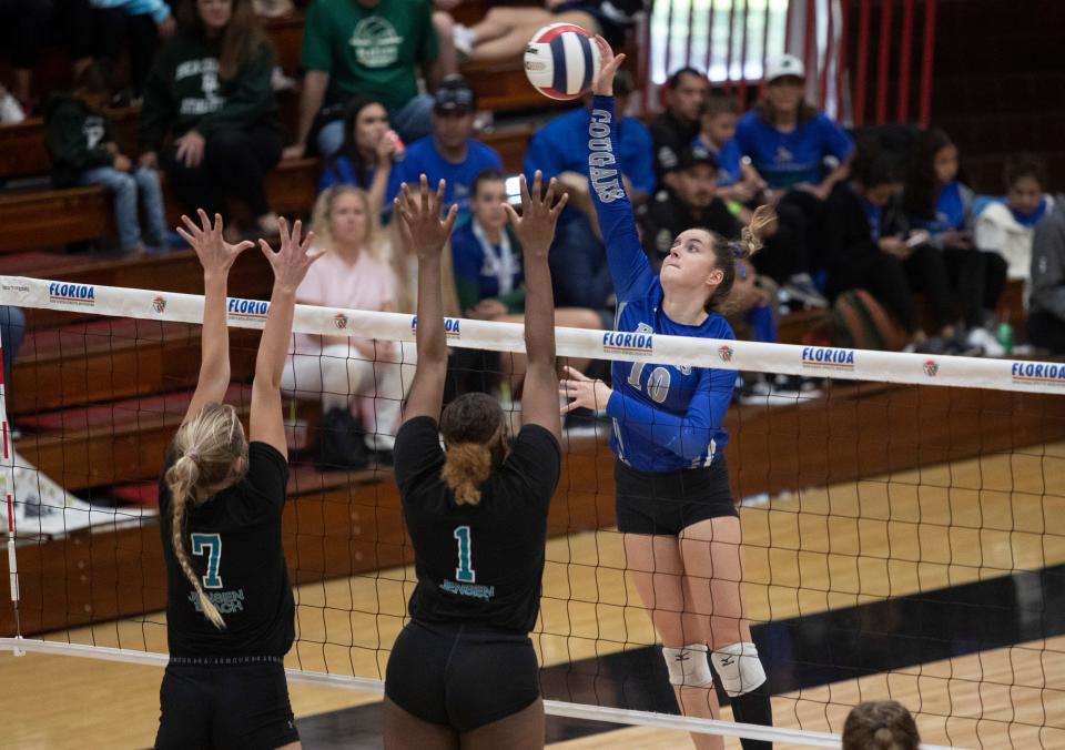 Keira Kruk of Barron Collier hits over Catherine Hamilton and Kiosha Smith of Jensen Beach in the FHSAA Class 5A volleyball state championship on Saturday, Nov. 12, 2022, at Polk State College in Winter Haven.