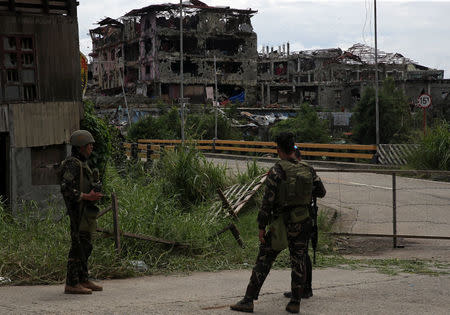 Soldiers stand on guard and look at damaged buildings and houses after government troops cleared the area from pro-Islamic State militant groups inside the war-torn area in Saduc proper, Marawi city, southern Philippines October 22, 2017. REUTERS/Romeo Ranoco