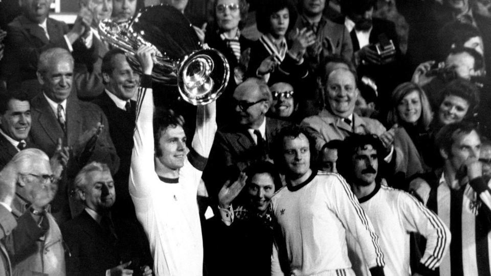Wearing the captain's armband, Beckenbauer hoists the European Cup with Bayern Munich. - S&G/PA Images/Getty Images