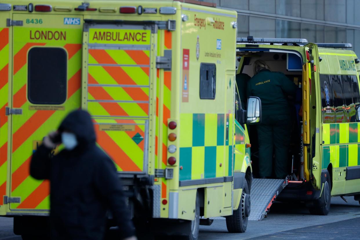 <p>A person wearing a face mask to curb the spread of coronavirus walks past ambulances outside the Royal London Hospital in east London</p> (AP)