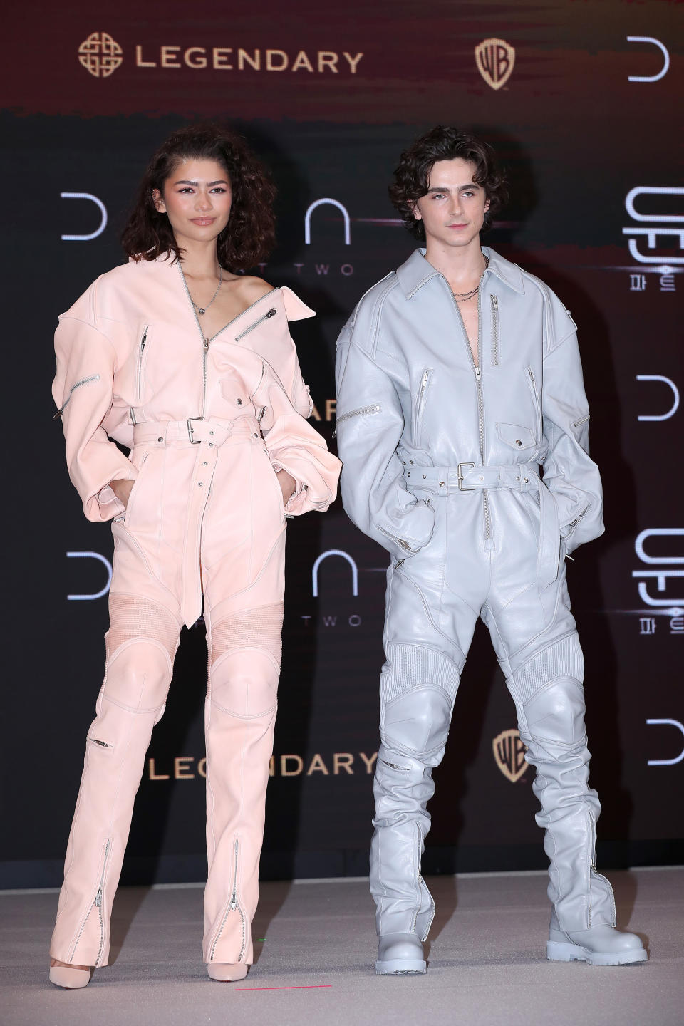Zendaya and Timothee Chalamet wearing matching leather jumpsuits in pink and blue respectively