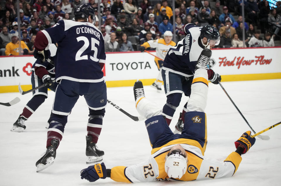 Nashville Predators right wing Nino Niederreiter, center, tumbles after losing the puck while driving between Colorado Avalanche right wing Logan O'Connor, left, and left wing J.T. Compher in the second period of an NHL hockey game Saturday, Dec. 17, 2022, in Denver. (AP Photo/David Zalubowski)