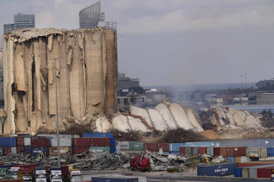 A collapsed portion, right, lies on the ground of the silos that damaged during the August 2020 massive explosion in the port, in Beirut, Lebanon, Tuesday, Aug. 23, 2022. The ruins of the Beirut Port silos' northern block that withstood a devastating port explosion two years ago has collapsed. The smoldering structure fell over on Tuesday morning into a cloud of dust, leaving the southern block standing next to a pile of charred ruins. (AP Photo/Hussein Malla)