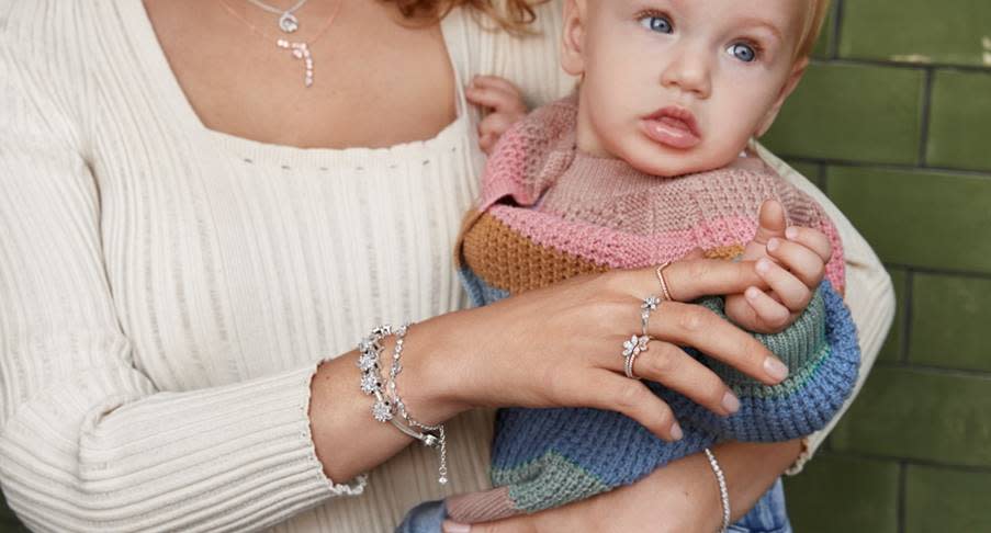 Mother wearing Pandora jewellery holding on to a baby. 