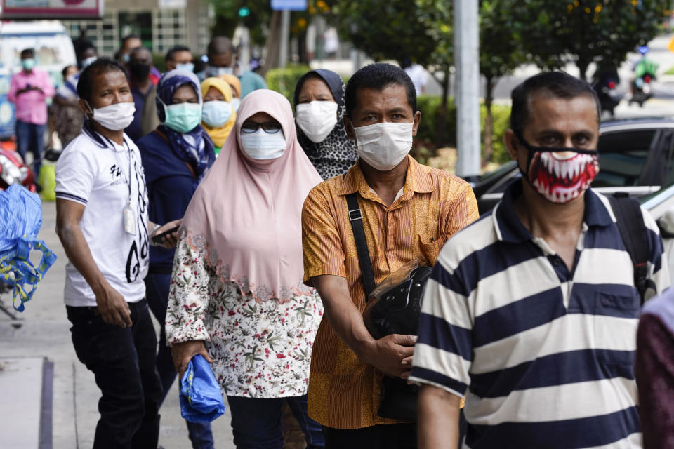 Muslims wearing masks wait outside a wet market in downtown Kuala Lumpur, Malaysia, Friday, April 24, 2020. Malaysia, along with neighboring Singapore and Brunei, has banned popular Ramadan bazaars where food, drinks and clothing are sold in congested open-air markets or road-side stalls. The bazaars are a source of key income for many small traders, some who have shifted their businesses online. (AP Photo/Vincent Thian)
