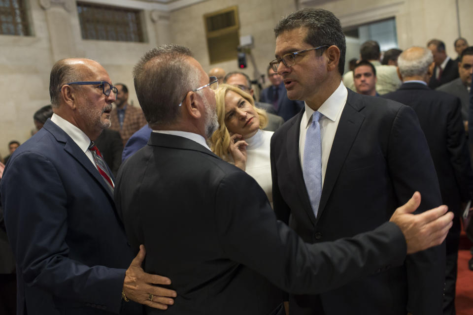 Proposed Secretary of State Pedro Pierluisi, right, is greeted by lawmakers Luis Ortiz and Jose Aponte during a break in his confirmation hearing at the House of Representatives, in San Juan, Puerto Rico, Friday, August 2, 2019. As Gov. Ricardo Rossello is expected to leave office in a few hours, the Puerto Rican House of Representatives is expected to vote on Pierluisi's confirmation Friday afternoon. If he is rejected, Justice Secretary Wanda Vazquez automatically becomes governor as the next in the order of succession, even though she has said she would unwillingly accept the job. (AP Photo/Dennis M. Rivera Pichardo)