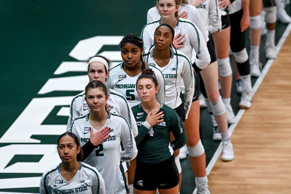 Michigan State's Jamye Cox, right, and the rest of the Spartans stand for the national anthem before the volleyball match against Michigan on Wednesday, Feb. 17, 2021, at the Jenison Field House in East Lansing. Michigan won the set 25-22.