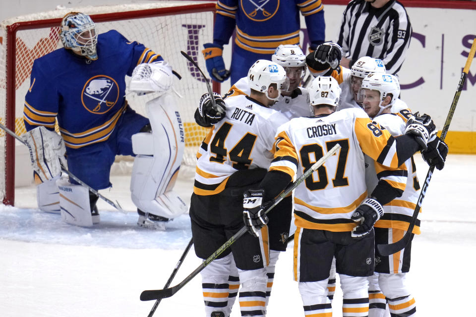 Pittsburgh Penguins' Sidney Crosby (87) is congratulated after scoring against Buffalo Sabres goaltender Ukko-Pekka Luukkonen during the first period of an NHL hockey game in Pittsburgh, Saturday, Dec. 10, 2022. (AP Photo/Gene J. Puskar)