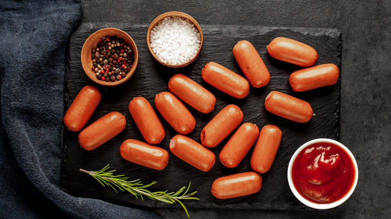 Mini hot dogs with seasoning in bowls