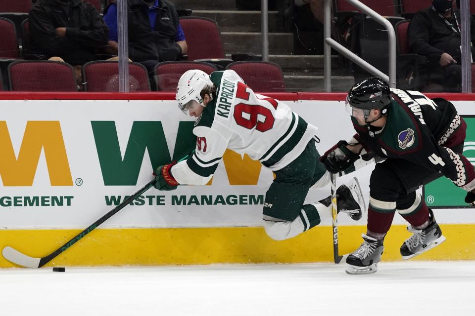 Minnesota Wild left wing Kirill Kaprizov (97) gets tripped by Arizona Coyotes defenseman Niklas Hjalmarsson (4) during the second period of an NHL hockey game Wednesday, April 21, 2021, in Glendale, Ariz. (AP Photo/Ross D. Franklin)