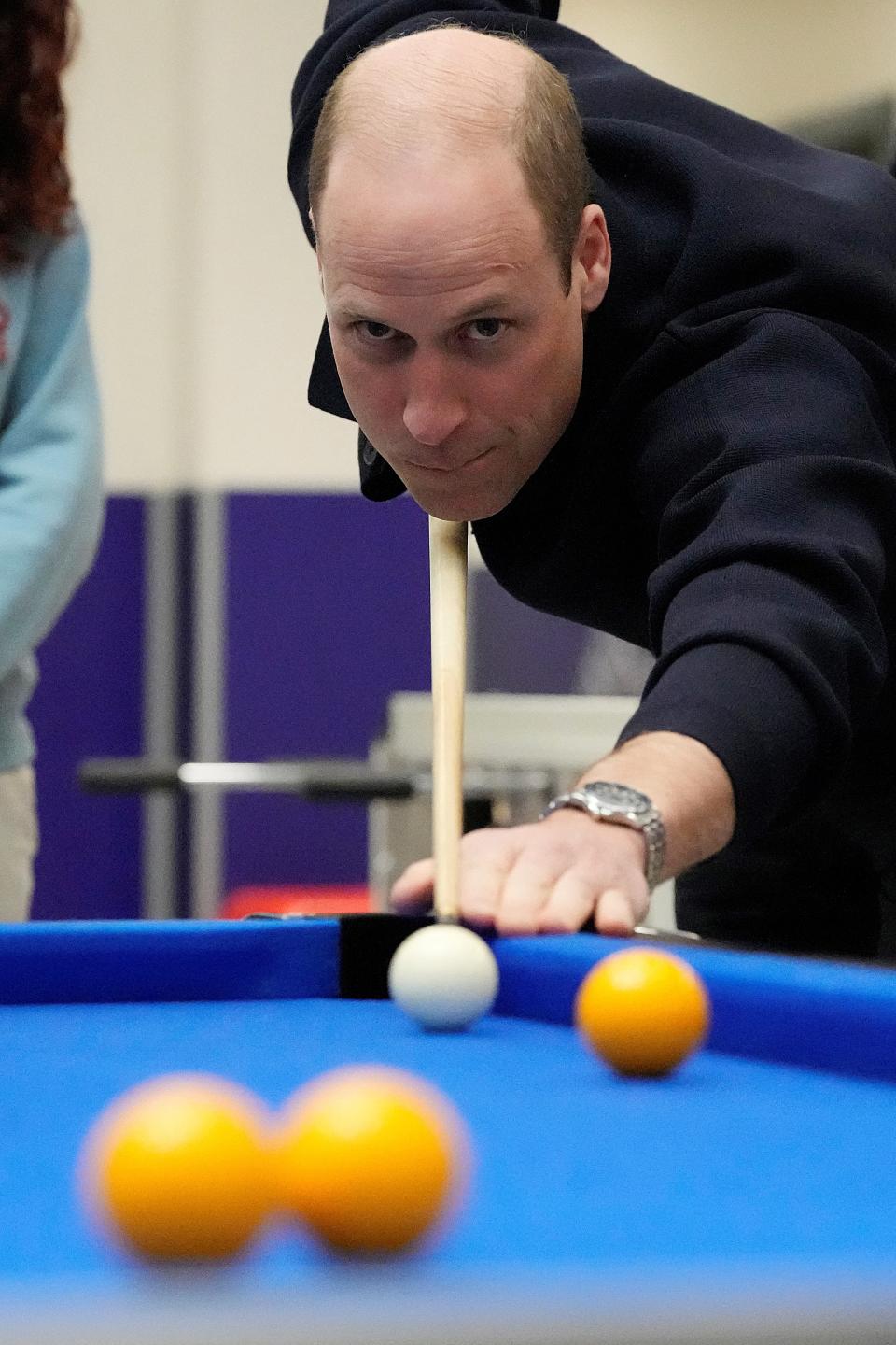 William playing pool, focusing on cueing the white ball