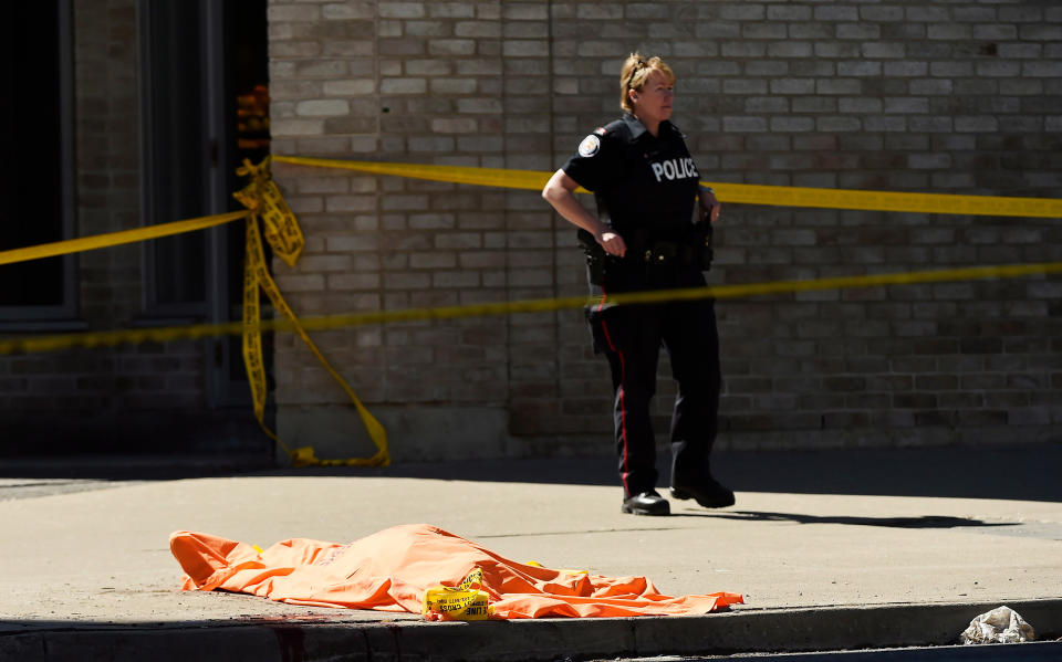 <p>A police officer stands over a covered body in Toronto after a van mounted a sidewalk crashing into a number of pedestrians on Monday, April 23, 2018. (Photo: Nathan Denette/Canadian Press) </p>