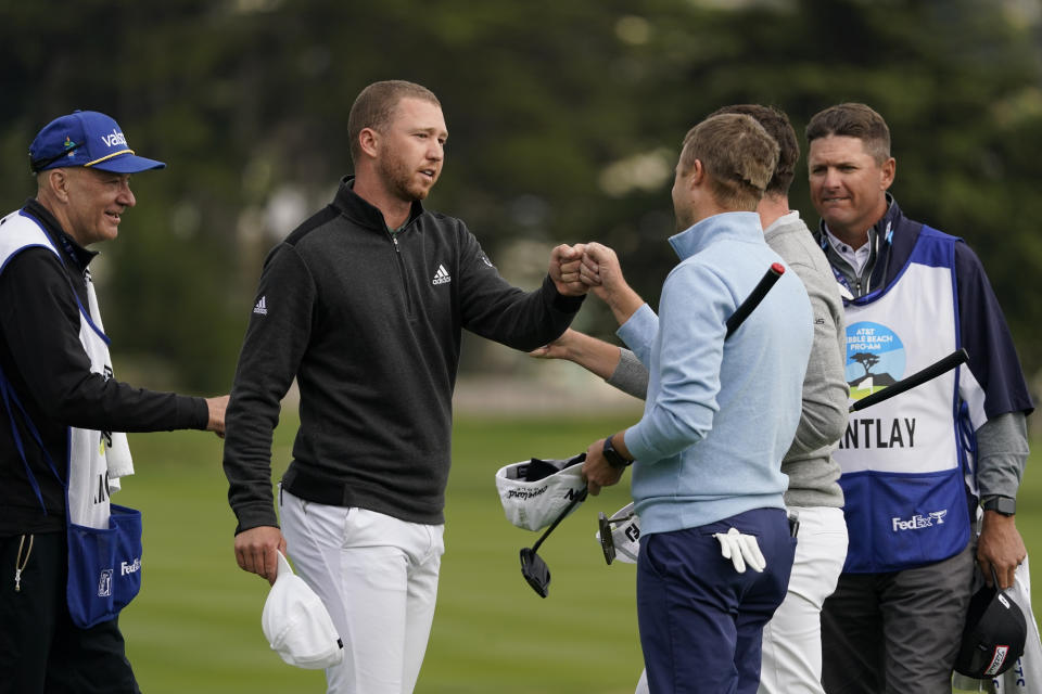 Daniel Berger, second from left, is greeted by playing partners Patrick Cantlay, second from right, and Russell Knox, third from right, on the 18th green of the Pebble Beach Golf Links after finishing the final round of the AT&T Pebble Beach Pro-Am golf tournament Sunday, Feb. 14, 2021, in Pebble Beach, Calif. Berger won the tournament. (AP Photo/Eric Risberg)