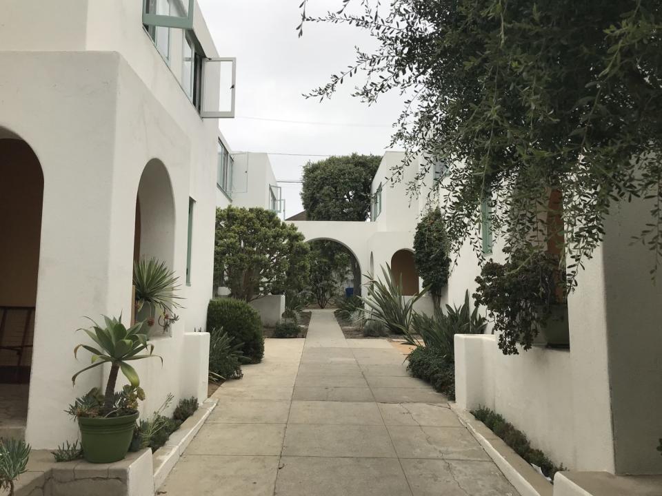 A series of elegant Modern arches painted in white surround a courtyard space studded with plants.