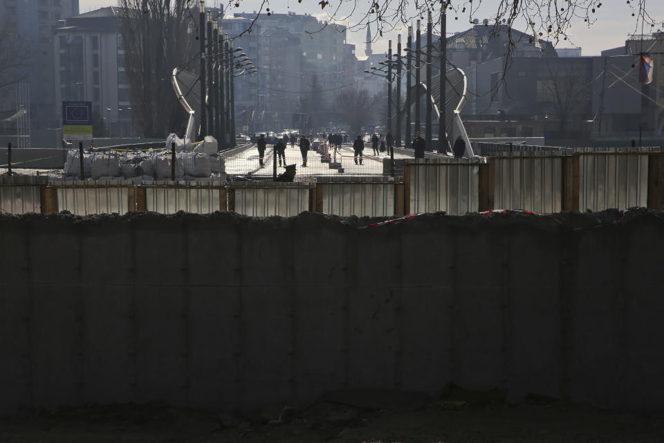 Ethnic Albanians walk in the bridge near a concrete wall erected in the northern city of Mitrovica on Sunday, Jan. 5, 2017, that has provoked tensions between Kosovo and neighboring Serbia as it was being pulled down. The move followed an agreement between the government with the country's ethnic Serb minority, facilitated by the European Union and the United States embassy . (AP Photo/Visar Kryeziu)