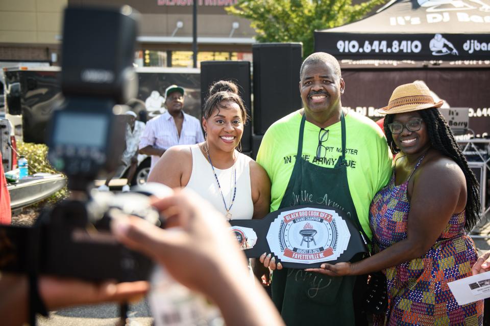 Spring Lake Mayor Kia Anthony, left, and Fayetteville City Council member Shakeyla Ingram hand the Grand Champion belt to Antoine Sadler, of In the Army Que, at the 2nd annual Black BBQ Cook Off on Saturday, Aug. 19, 2023, at Murchison Marketplace.