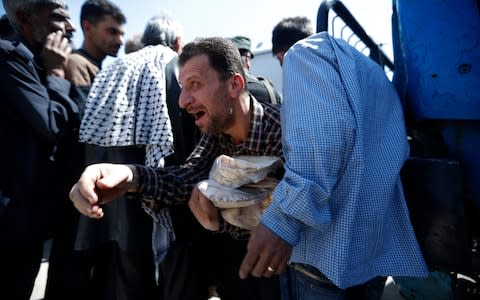 A Syrian man holds bread as Syrian authorities distributed bread, vegetables and pasta to Douma residents, in the town of Douma, the site of a suspected chemical weapons attack - Credit: AP