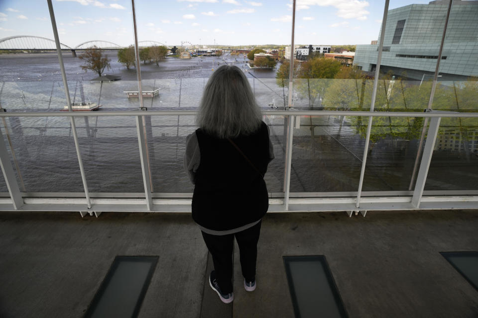 Michelle Javornik, of Davenport, Iowa, looks out at floodwaters from the nearby Mississippi River, Monday, May 1, 2023, in Davenport, Iowa. The rising Mississippi River is testing flood defenses in southeast Iowa and northwest Illinois as it nears forecast crests in the area Monday, driven by a spring surge of water from melting snow. (AP Photo/Charlie Neibergall)