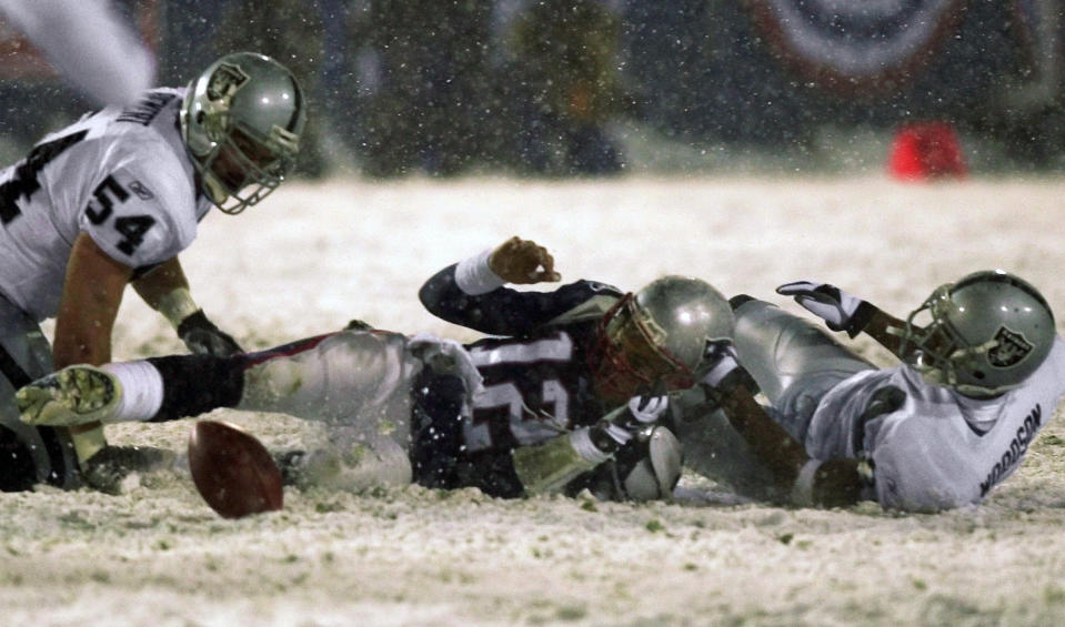 FILE - New England Patriots quarterback Tom Brady (12) loses the ball after being brought down by Oakland Raiders' Charles Woodson, right, while Raiders' Greg Biekert (54) moves to recover the ball in the fourth quarter of their AFC Division Playoff game on Jan. 19, 2002, in Foxborough, Mass. With the Patriots trailing the Raiders 13-10 in the final two minutes, Brady went back to pass and had the ball knocked out by former Michigan teammate Woodson. The Raiders recovered the apparent and celebrated only to have the call reversed on replay by referee Walt Coleman because of the little-known Tuck Rule that was later eliminated. (AP Photo/Elise Amendola, File)