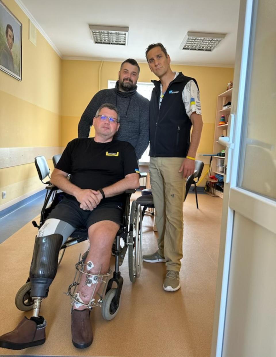 During his visit to a recently-opened mental health center in Lviv, Ukraine last year, JustAnswer CEO Andy Kurtzig, right, posed with a staffer, left, and a Ukrainian soldier who had part of his right leg amputated after fighting in the war with Russia.