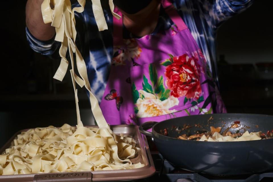 Strands of pappardelle are transferred to a skillet.