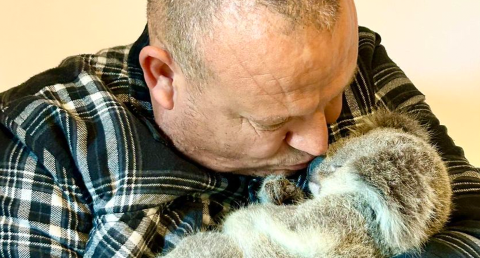 Close up of Richardo Lonza holding a dead baby koala and kissing it.