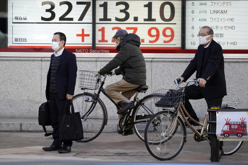 People wait for traffic signals to change in front of an electronic stock board showing Japan's Nikkei 225 index at a securities firm Tuesday, Nov. 14, 2023, in Tokyo. Asian shares were mostly higher Tuesday ahead of potentially market-moving developments, including a U.S.-China summit and data releases from the U.S., Japan and China. (AP Photo/Eugene Hoshiko)