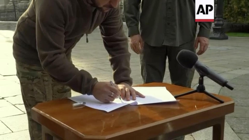 In this image made from video, Ukrainian President Volodymyr Zelenskyy signs an application for ''accelerated accession to NATO'' in Kyiv, Ukraine, Friday Sept. 30, 2022. (AP Photo)