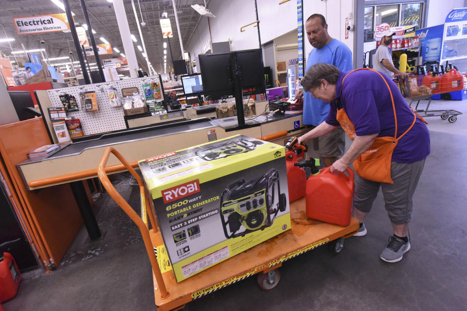 FILE - In this Sept. 2, 2019, file photo Delma Hewitt checks out Al Lombardi as he purchases a new generator and other supplies at the Home Depot in Monkey Junction, N.C. Backup power options range from gasoline-powered portable generators, which can cost $1,000 or more, to solar panels plus batteries, which cost tens of thousands of dollars to purchase and install. (Ken Blevins/The Star-News via AP, File)