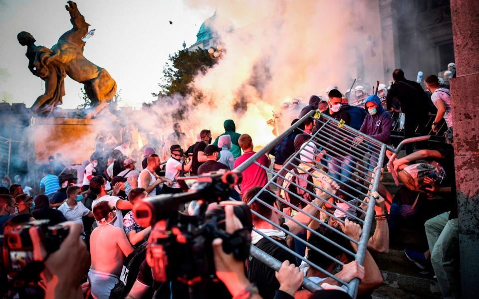 Protesters clash with police in front of Serbia's parliament in Belgrade for a second consecutive night on Wednesday over plans to re-impose lockdown to counter a surge in coronavirus  -  ANDREJ ISAKOVIC/AFP