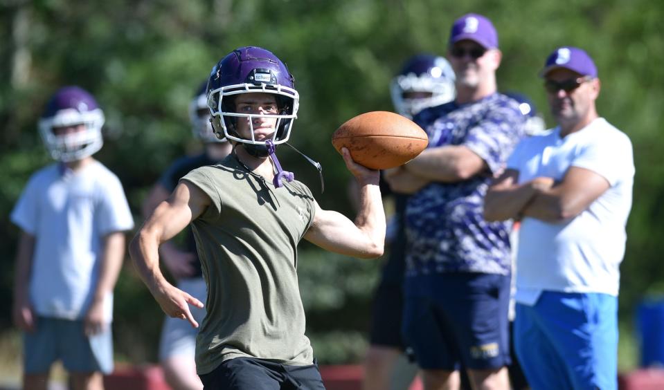 Ty Kelley works on a passing drill as the coaching staff looks on during a Saturday morning early season workout on the school's practice field for the Bourne football squad.