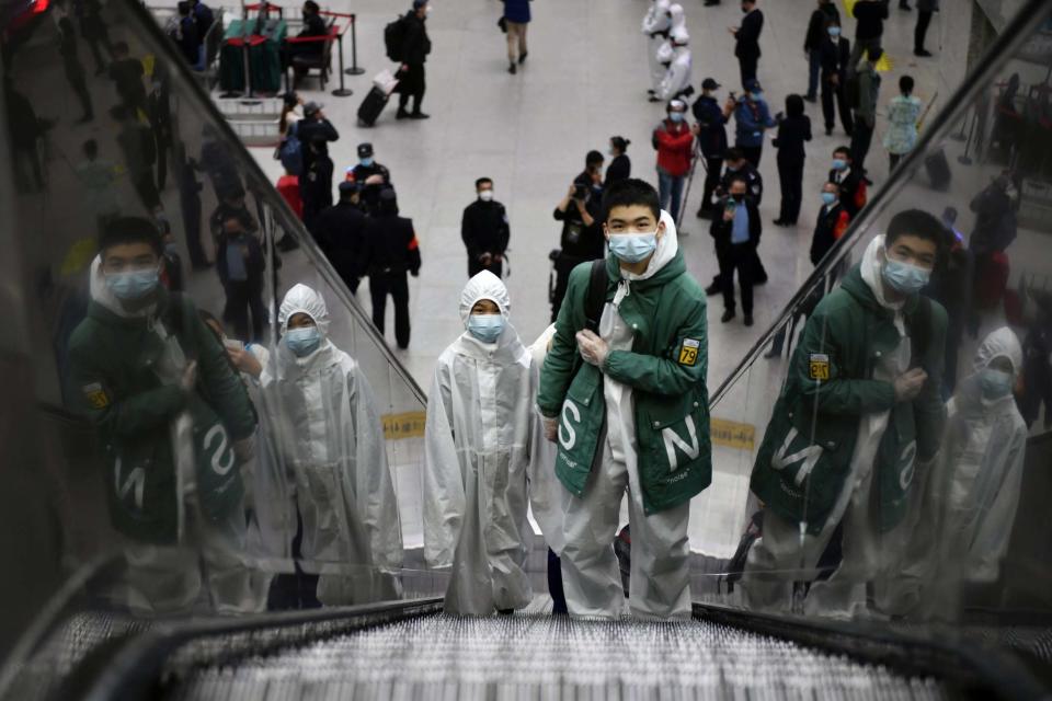 Travellers wearing protective gear ride an escalator at Wuchang Railway Station (REUTERS)