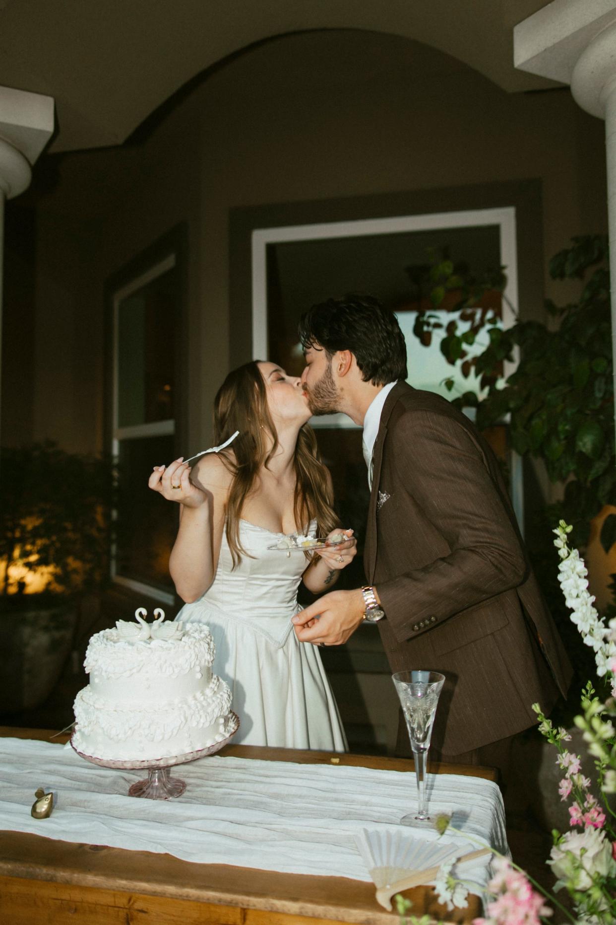 A bride and groom kiss after cutting their wedding cake.