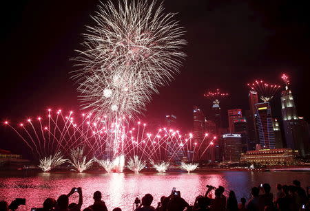 People take photos of fireworks in the skyline of Singapore during a National Day Golden Jubilee parade rehearsal July 25, 2015. The city-state's 50th independence falls on August 9. REUTERS/Edgar Su