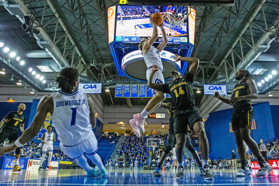 Blue Hens guard Cavan Reilly (3) scores on the rebound against Division II Goldey-Beacom Lightning guard Zakari McQueen (14) during the 2023-24 basketball home opener at University of Delaware’s Bob Carpenter Center in Newark, Wednesday, Nov. 8, 2023. Blue Hens won 101-68.