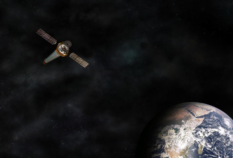 A T-shaped spacecraft over a brown, green and blue sphere