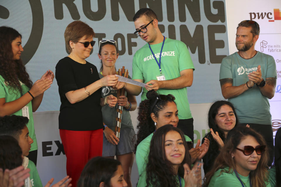 Scotland's First Minister Nicola Sturgeon receives a written declaration from runners and organizers at the finish line of the Running Out Of Time climate relay, which arrived from Glasgow, Scotland after 40 days through 18 countries to reach the COP27 U.N. Climate Summit, at the Park Regency Hotel on Tuesday, Nov. 8, 2022, in Sharm el-Sheikh, Egypt. (AP Photo/Thomas Hartwell)