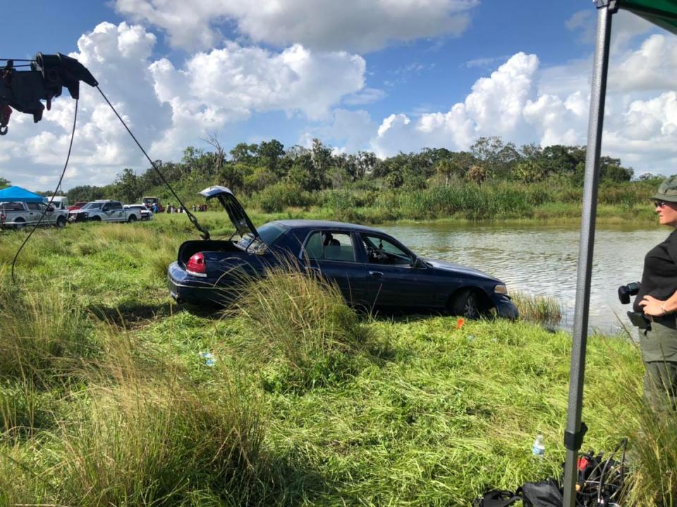 A tow truck pulls a car first responders found at the bottom of an Indiantown pond where two bodies were found Monday.