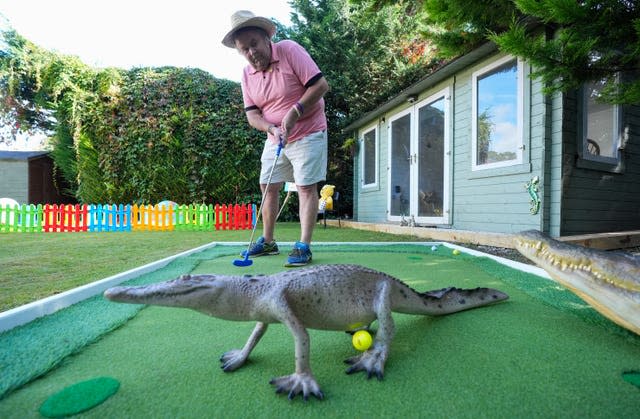 David Lawrence on a crazy golf hole putting a ball under a plastic lizard