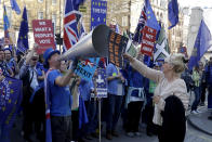 FILE - In this Wednesday, Feb. 27, 2019 file photo, a supporter of Britain's departure from the European Union, at right, holds a placard up in front of supporters of remaining in the EU, including Stop Brexit Man, Steve Bray, with his foghorn, outside Parliament in London. Five years ago, Britons voted in a referendum that was meant to bring certainty to the U.K.’s fraught relationship with its European neigbors. Voters’ decision on June 23, 2016 was narrow but clear: By 52 percent to 48 percent, they chose to leave the European Union. It took over four years to actually make the break. The former partners are still bickering, like many divorced couples, over money and trust. (AP Photo/Matt Dunham, File)