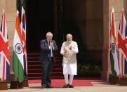 Indian Prime Minister Narendra Modi watches his British counterpart Boris Johnson greet the gathering upon the latter's arrival for delegation level talks in New Delhi, Friday, April 22, 2022. Johnson is expected to help move India away from its dependence on Russia by expanding economic and defense ties when he meets with his Indian counterpart Friday, officials said. (AP Photo/Manish Swarup)